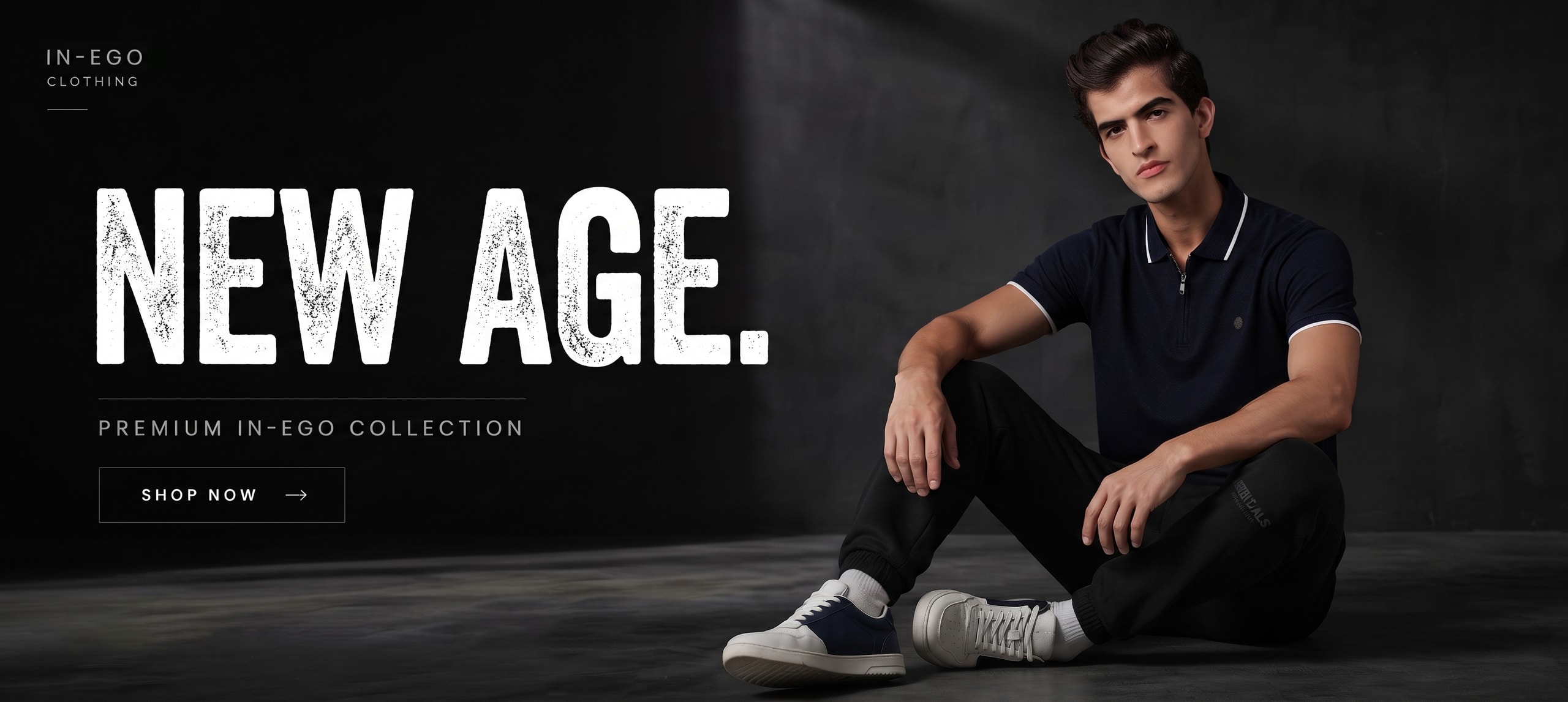 A man in a navy zip-collar polo and black joggers sitting against a dark concrete wall, beside the words “IN-EGO Clothing - New age. - Premium IN-EGO collection - Shop now”.